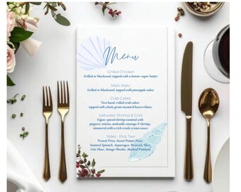May include: A white menu card with a blue seashell design and the word "Menu" in script. The menu lists grilled chicken, mahi mahi, crab cakes, and saltwater shrimp & grits. Gold-colored forks, knife, and spoon are on the right.
