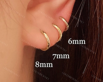 May include: Three gold hoop earrings in different sizes, 6mm, 7mm, and 8mm, shown on a person's ear.