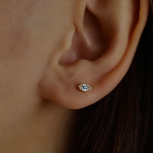May include: A gold evil eye earring with a blue center stone and white diamond accents.