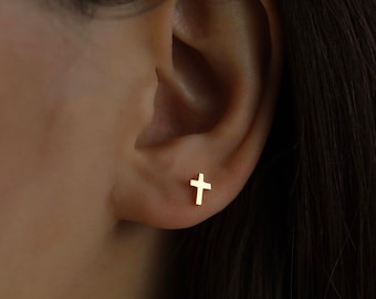 May include: A close-up of a person's ear with a small gold cross earring.