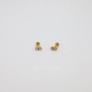 May include: A pair of gold-toned earrings with a blue and white eye design. The earrings are small and delicate, and they would make a great gift for someone who loves unique jewelry.