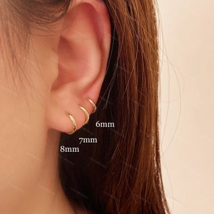 May include: Close-up of a person's ear with three gold hoop earrings. The earrings are 6mm, 7mm, and 8mm in diameter.