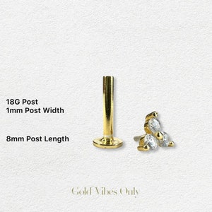 May include: Gold body jewelry with three clear cubic zirconia stones. The jewelry is 18 gauge and has an 8mm post length.