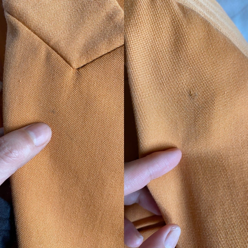 May include: Close-up of a mustard yellow fabric with a subtle texture. The fabric has a small, light brown stain.