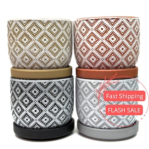 May include: Set of four ceramic planters with geometric patterns. The planters are in black and white, brown and white, and red and white. Each planter has a matching saucer.