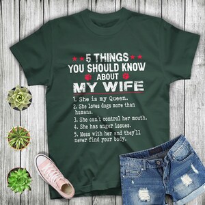 May include: A green t-shirt with a white graphic that says "5 Things You Should Know About My Wife" and lists five reasons why. The graphic is in a distressed font.