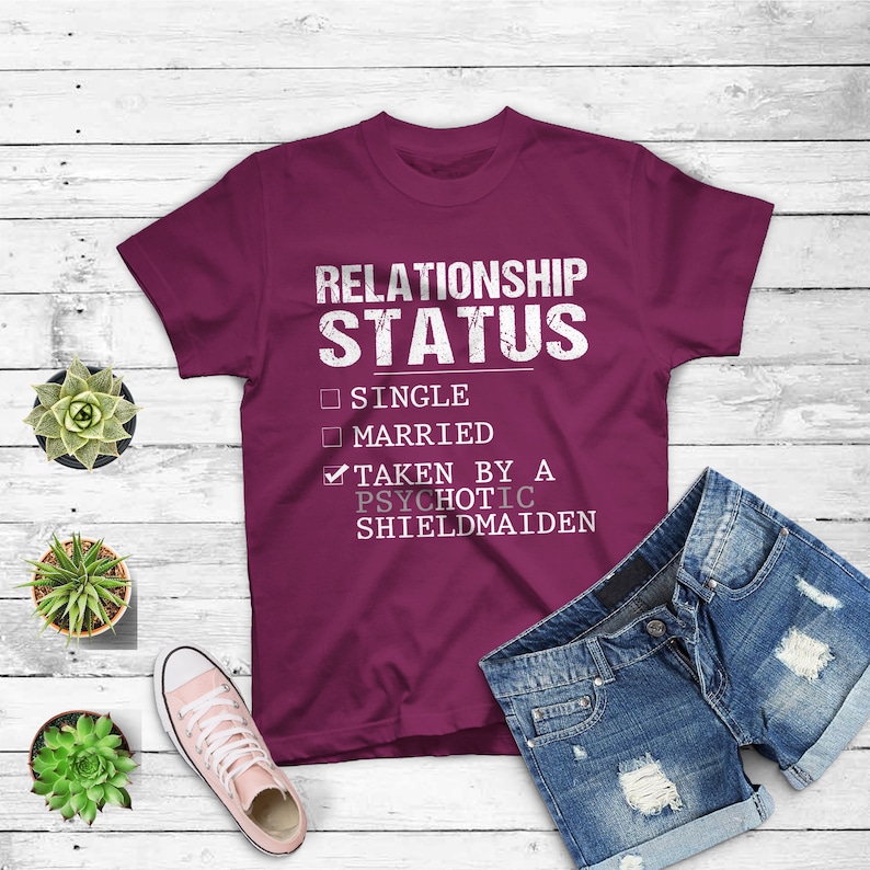 May include: Burgundy t-shirt with a white graphic that reads "Relationship Status" with checkboxes for "Single", "Married", and a checkmark for "Taken by a Psychotic Shieldmaiden".