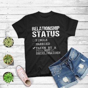 May include: Black t-shirt with white text that reads "Relationship Status" with checkboxes for "Single", "Married", and "Taken by a Psychotic Shieldmaiden". The "Taken by a Psychotic Shieldmaiden" box is checked.