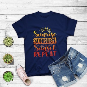 May include: A navy blue t-shirt featuring a graphic design that reads "Sunrise Sunburn Sunset Repeat" in a colourful, sunset-inspired font.