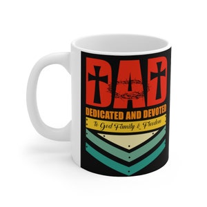 Peut inclure: Une tasse en céramique blanche avec un motif noir et rouge. Le motif représente le mot "DAD" avec une croix de chaque côté et une couronne d'épines au centre. Sous le mot "DAD" se trouve le texte "DEDICATED AND DEVOTED to God Family & Freedom". Le motif comprend également une série de trois chevrons en vert, jaune et bleu.