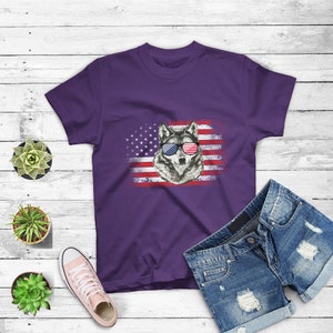 May include: Purple t-shirt with a wolf wearing sunglasses in front of an American flag.