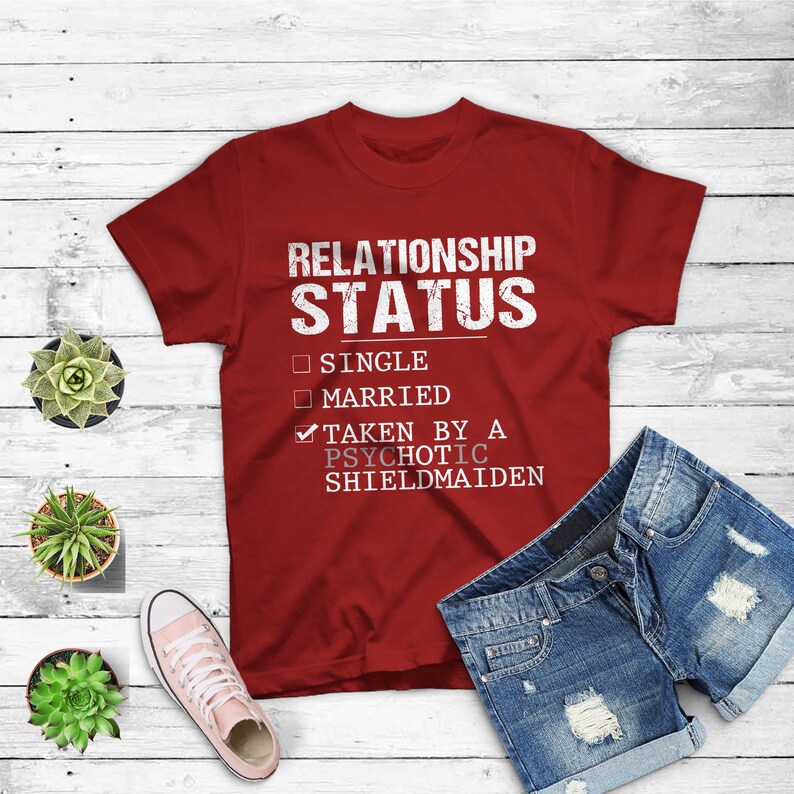 May include: Red t-shirt with a white graphic that says "Relationship Status" with a checkmark next to "Taken by a Psychotic Shieldmaiden" and unchecked boxes next to "Single" and "Married".