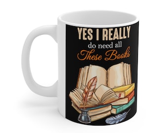 May include: White ceramic mug with a black background and the text "YES I REALLY do need all These Books" in a vintage font. An illustration of a stack of books with a quill pen and inkwell is on the right side of the mug.