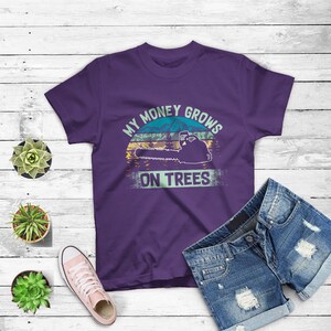 May include: Purple t-shirt with a vintage-style graphic of a chainsaw and the text "My money grows on trees".