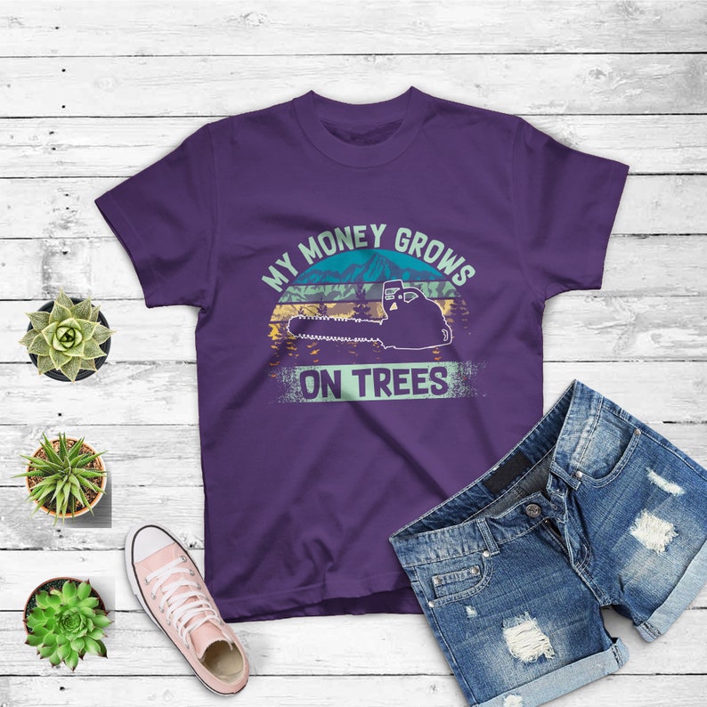 May include: Purple t-shirt with a vintage-style graphic of a chainsaw and the text "My money grows on trees".