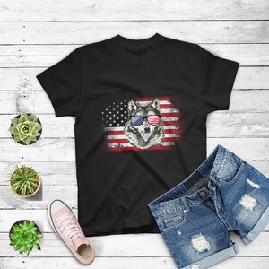 May include: Black t-shirt with a wolf wearing red, white, and blue sunglasses in front of an American flag.