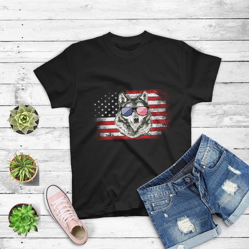 May include: Black t-shirt with a wolf wearing red, white, and blue sunglasses in front of an American flag.