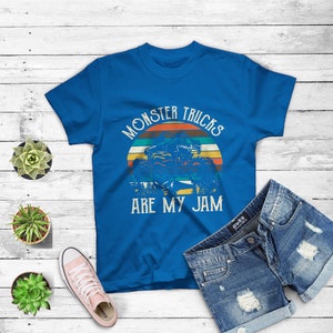 Puede incluir: Una camiseta azul real con un gr&aacute;fico de estilo vintage de un cami&oacute;n monstruo. El gr&aacute;fico presenta una puesta de sol con el texto "Monster Trucks Are My Jam".