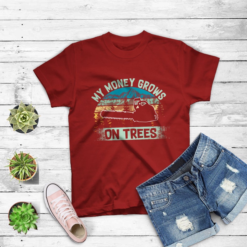 May include: Red t-shirt with a vintage-style graphic of a chainsaw and the text "My money grows on trees".