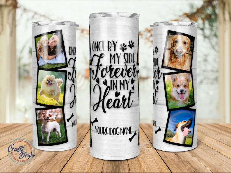 May include: White stainless steel tumbler with a woodgrain background. The tumbler features a black paw print design and the text "Once by my side forever in my heart."  The tumbler also features a collage of dog photos.