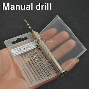 May include: A silver manual drill with a set of drill bits in a clear plastic case. The drill bits are labeled in millimeters: 1.0, 1.2, 1.5, 1.8, 2.0, 2.5, 3.0, 3.5, and 4.0.