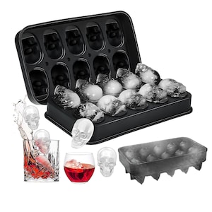 Può includere: Vassoio per cubetti di ghiaccio in silicone nero a forma di teschio con 15 stampi per cubetti di ghiaccio a forma di teschio. Il vassoio è aperto e pieno di cubetti di ghiaccio trasparenti. Ci sono anche diversi cubetti di ghiaccio a forma di teschio su una superficie bianca.