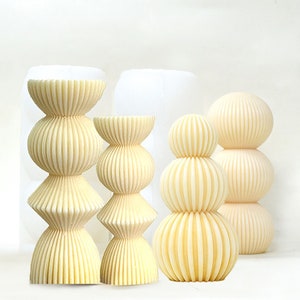 Può includere: Tre candele decorative con un design a coste. Le candele sono di diverse dimensioni e sono tutte di colore giallo pallido.