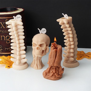 Peut inclure: Trois bougies décoratives en forme de crâne, d'épine dorsale et de souche d'arbre. Les bougies sont toutes de couleur beige et marron. La bougie en forme de crâne a un petit autocollant blanc qui dit "Smile".