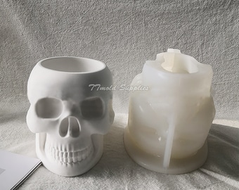 May include: White skull-shaped planter mold and a finished planter made from the mold. The mold is made of silicone and is flexible. The planter is made of concrete and is a solid, white skull.