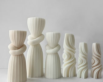 May include: Six white ceramic candle holders with different designs. The holders are arranged in a row from largest to smallest. The holders are all white and have a smooth, glossy finish.