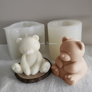 May include: Two silicone molds for making bear-shaped candles. One mold is white and the other is brown. The molds are shown with finished candles.