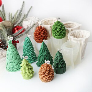 May include: Assortment of Christmas tree and pine cone shaped candles in green and brown. The candles are displayed next to their silicone moulds.