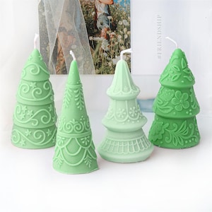 Könnte beinhalten: Vier grüne Weihnachtsbaumkerzen mit filigranen Designs. Die Kerzen sind aus Wachs und haben eine matte Oberfläche. #FRIENDSHIP