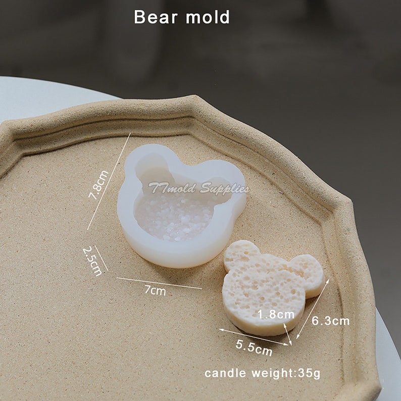 Puede incluir: Molde de silicona blanco en forma de oso con un di&aacute;metro de 7 cm y una altura de 7,8 cm. El molde se muestra con una vela blanca en forma de oso de 6,3 cm de ancho y 5,5 cm de alto. La vela pesa 35 gramos.