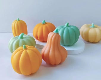 Peut inclure: Une collection de six petites citrouilles en céramique peintes à la main dans différentes nuances d'orange, de vert et de jaune. Les citrouilles sont disposées sur une surface blanche.