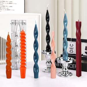 Puede incluir: Surtido de seis velas decorativas en varios colores y diseños. Las velas están retorcidas y tienen forma de espiral. Algunas velas están en candelabros de plata. Las velas están sobre una superficie blanca con un calendario en el fondo.