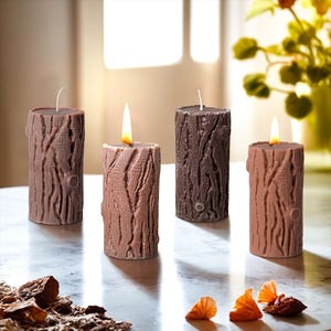 May include: Four brown and beige pillar candles with a tree bark texture. The candles are lit and are arranged in a row on a white surface.