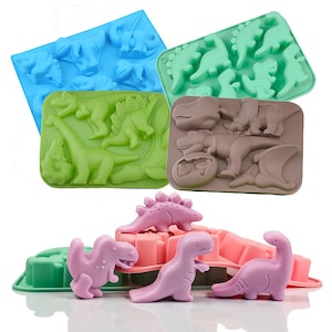 May include: A collection of colorful silicone dinosaur molds in blue, green, and brown. The molds feature various dinosaur shapes, and there are also several pink dinosaur figurines. These are ideal for making themed treats.