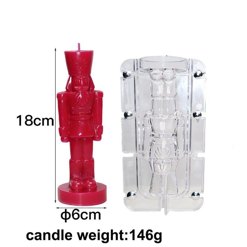 May include: A red candle shaped like a nutcracker soldier, standing 18cm tall with a diameter of 6cm. The candle weighs 146g. A clear plastic mold in the shape of the nutcracker is also shown. The candle has a detailed uniform and hat.