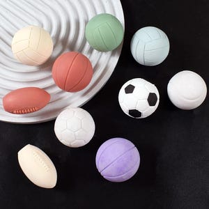 May include: A collection of ten different sports balls, including a football, soccer ball, basketball, volleyball, baseball, and tennis ball. The balls are all made of different materials and colors.