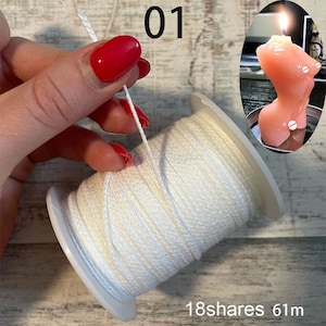 Puede incluir: Una bobina de cordón blanco con una longitud de 61 metros. El cordón está siendo sujetado por una mano con esmalte de uñas rojo. El texto "01" y "18shares" es visible en la imagen.