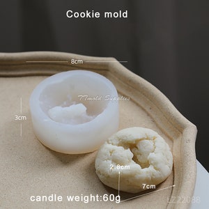 Puede incluir: Molde de galletas de silicona blanco con una profundidad de 3 pulgadas y un di&aacute;metro de 8 pulgadas. El molde se muestra con una galleta blanca que tiene 2,8 cm de di&aacute;metro y 7 cm de ancho. La galleta est&aacute; etiquetada como "peso de la vela: 60 g".