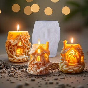 May include: Three lit, decorative house-shaped candles with intricate details, and a white mold. The candles are in shades of orange and yellow, with the flames glowing brightly. The background features bokeh lights.