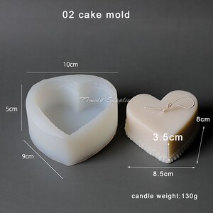 Puede incluir: Un molde para pastel de silicona blanco en forma de coraz&oacute;n con medidas en cent&iacute;metros. El molde mide 10 cm de ancho, 5 cm de alto y 9 cm de profundidad. Se muestra una vela terminada en forma de coraz&oacute;n junto al molde, con una cuerda atada a la parte superior. La vela mide 8,5 cm de ancho, 8 cm de alto y 3,5 cm de grosor. La vela pesa 130 gramos.