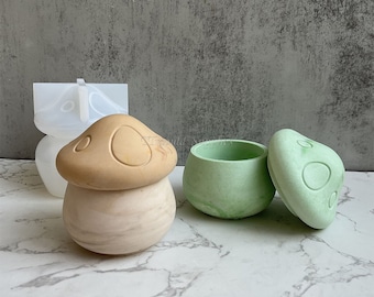 May include: Two mushroom-shaped containers, one in a light brown color and the other in a light green color. The containers are made of a smooth, textured material and have a lid that fits snugly on top.