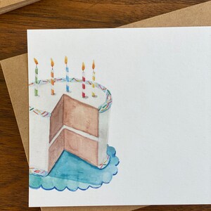 May include: A watercolour illustration of a birthday cake with blue icing and colourful sprinkles. The cake has a slice cut out and there are five lit candles on top.