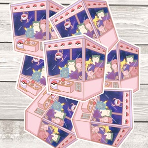 May include: A set of six pink and white sticker designs featuring a cartoon claw machine filled with various Pokemon characters. The claw machine has a starry night sky background and a pink and white color scheme.