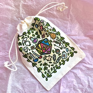 Puede incluir: Una bolsa de cord&oacute;n de color crema con un gr&aacute;fico colorido de un dado de m&uacute;ltiples caras, botellas de pociones, setas y otros elementos de fantas&iacute;a. El dise&ntilde;o est&aacute; enmarcado por vides y hojas verdes. La bolsa est&aacute; hecha de una tela suave y natural.