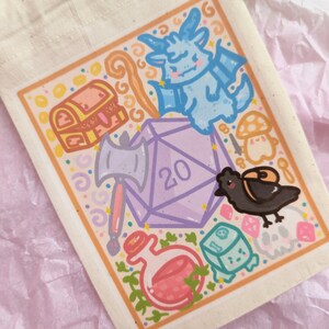 May include: A white drawstring bag with a colorful illustration of a 20-sided die, a chest, a dragon, a potion bottle, a crow, and other fantasy-themed items.