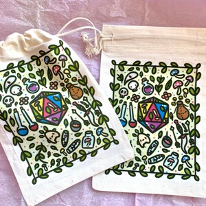 Puede incluir: Dos bolsas de cord&oacute;n de color crema con un dise&ntilde;o de tem&aacute;tica fant&aacute;stica. El dise&ntilde;o incluye un dado D20 multicolor, botellas de pociones, setas y otros elementos de fantas&iacute;a, enmarcados por hojas verdes. Una bolsa est&aacute; abierta, la otra cerrada.
